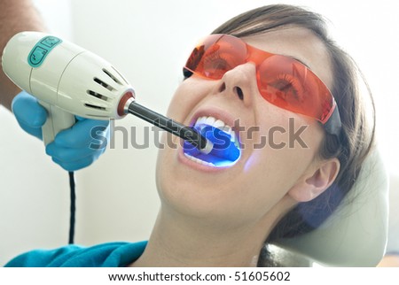 Woman getting her teeth whitened with UV technology at the dentist