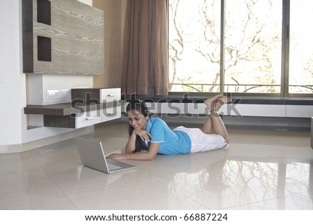 Young girl with a laptop in her room in window light
