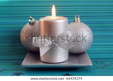 Christmas candle and two silver balls on blue background