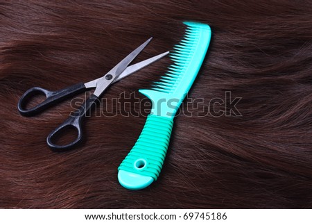 Texture of brunette long hair with green comb and scissors