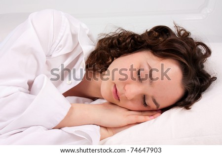 Beautiful young woman sleeps on the white bed