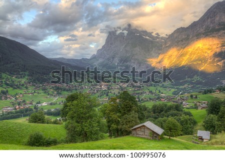 Famous alpine town Grindelwald in valley at sunset in front of mountain Eiger north face, Switzerland