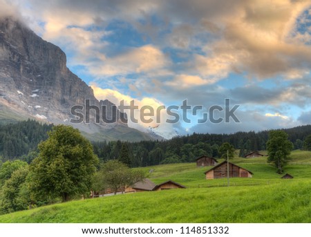 Mountain huts in valley at sunset in front of mountain Eiger north face, Switzerland