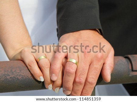 married couple holds hands and shows of there golden wedding rings