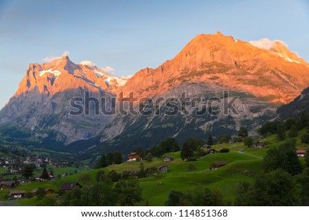 Alpenglow over alpine town Grindelwald in valley at sunset in front on mountain Eiger north face, Switzerland