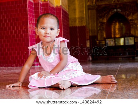 young burrmese girl dressed up nicely for temple visit with make up called thanaka ear rings, necklace and pink dress, Burma
