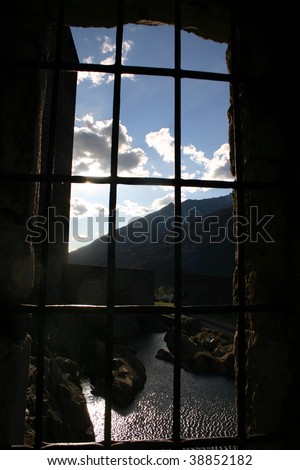 barred castle window looking out on gleaming pond