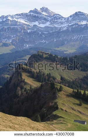 stretched winding mountain ridge in the background the snow crusted wall of mount Saentis