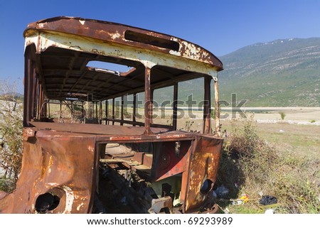 stripped rusty, old abandoned bus wreck in arid mountainous landscape of Montenegro