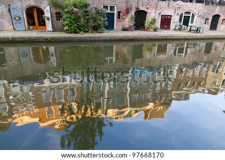 Canal and cellar wharfs in Utrecht, Netherlands. Vintage houses reflecting in water at sunset.