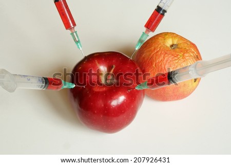 Apple and Orange with syringes. Genetically modified food.