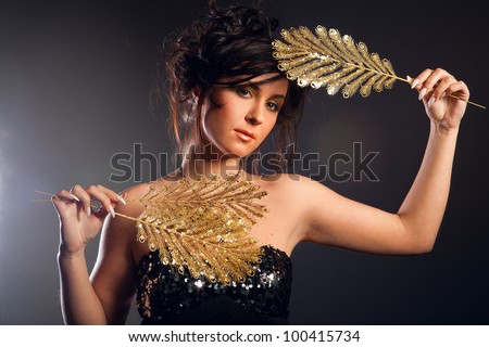 young girl holding an ornament of gold feathers
