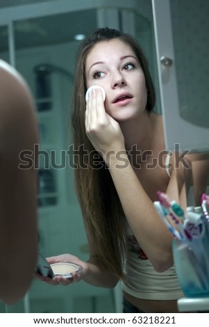 The girl does makeup in the bathroom