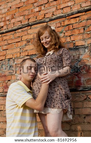 Portrait of a happy young man listen his pregnant wife belly . outdoor.