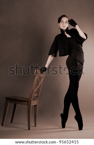 young ballerina performs exercises near the chair