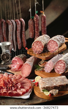 A classic still life of bacon, salami, sausage and pork gelatin on an old table