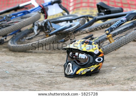 Shiny black and yellow biker\'s helmet dropped behind a cross bicycles.