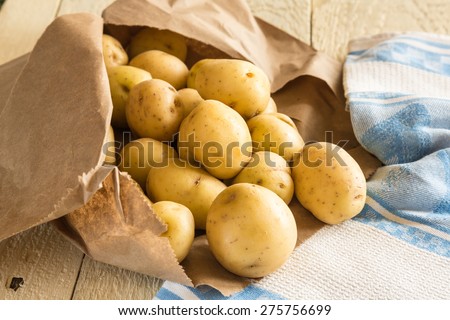 New potatoes on rustic table with brown paper bag