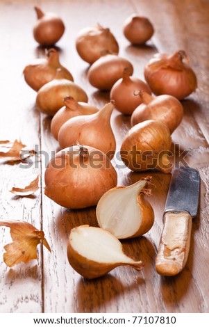 Small onions on a wooden table with one cut in half