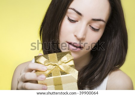 young woman opens a golden shiny gift box and looks inside