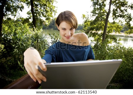 young woman with laptop in park relaxing in the sunshine