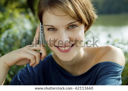 young woman talks outdoors with a cell phone in her hands