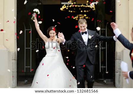 Just married couple under a rain of rose petals