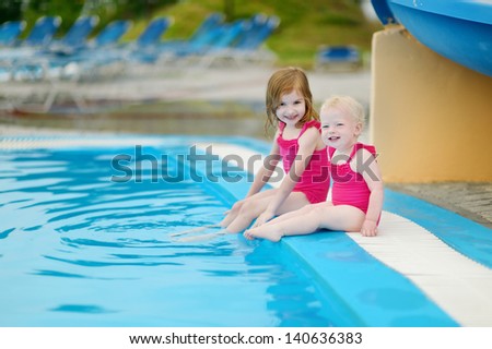 Two sisters sitting by a swimming pool