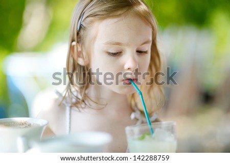 Adorable girl drinking lemonade in outdoor restaurant