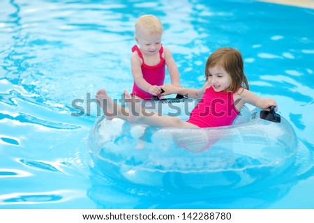 Little sisters having fun in a pool at summer