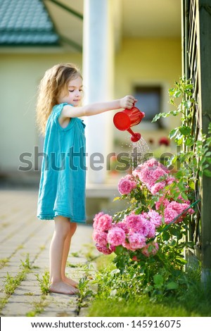 Cute little girl watering flowers in the garden