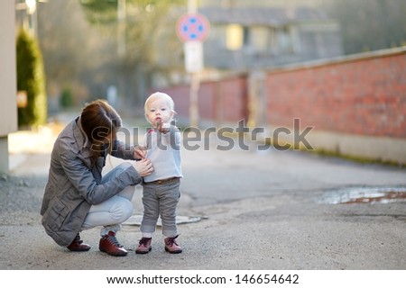 Young mother buttoning her daughters blouse