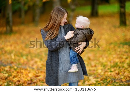 Young mother and her cute toddler daughter at fall