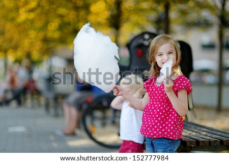 Adorable little girl eating candy-floss outdoors at summer