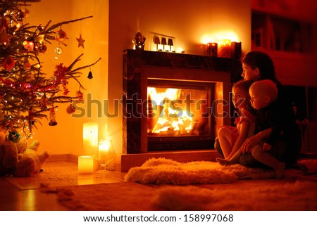 Young mother and her daughters by a fireplace on Christmas
