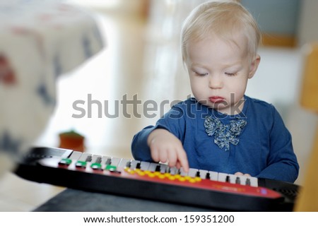Little toddler girl playing toy piano