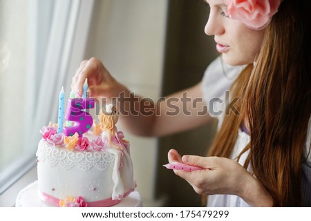 Young mother decorating her daughters birhtday cake