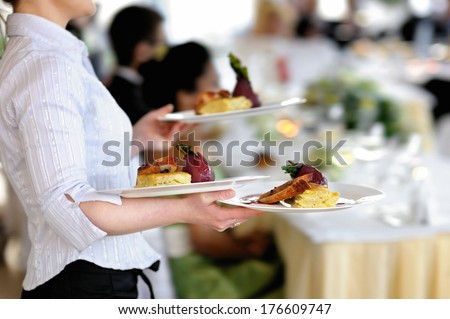 Waitress Carrying Three Plates With Meat Dish