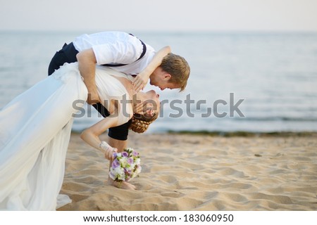 Beach wedding: bride and groom hugging by the sea