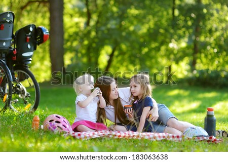 Young mother and her daughters picnicking in the park