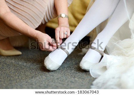 Mother helping a bride to put her wedding shoes on