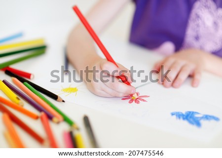 Cute preschooler girl drawing a picture with colorful pencils