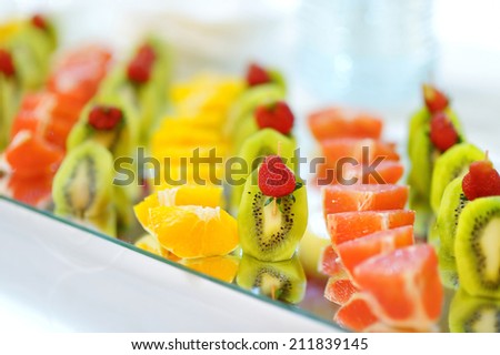 Plate full of sliced fresh oranges, strawberries, watermelons and kiwi on a festive table