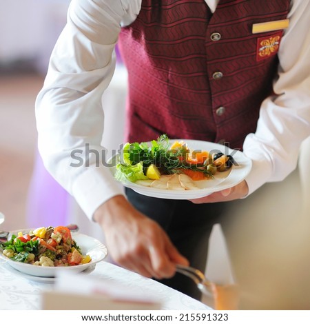Waiter carrying a plate with meat dish
