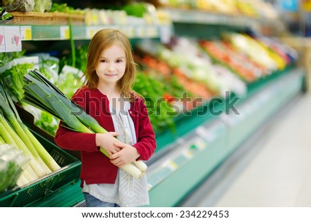 Little girl choosing a leek in a food store