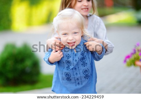 Two cute little sisters having fun running and laughing on a sunny summer day