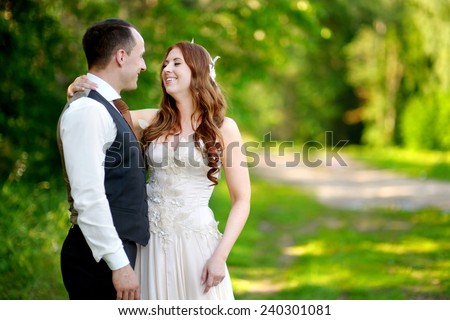 Young bride and groom hugging and kissing in beautiful summer park