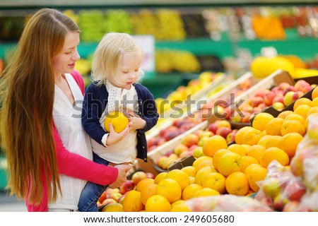 Mother and daughter choosing an orange in a fruit store
