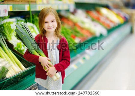 Little girl choosing a leek in a food store
