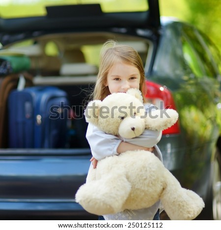 Adorable little girl with big teddy bear leaving for a car vacation with their parents
